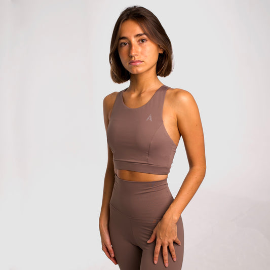 Women's beige sports top. Long cut bra. Elastic chest strap for comfort and support. Lightweight, breathable and comfortable bra. Removable cups. Top deportivo de mujer color beige. Sujetador de corte largo. Tira elástica en el pecho ofreciendo comodidad y sujeción. Sujetador cómo, ligero y transpirable. Top con copas extraibles. 