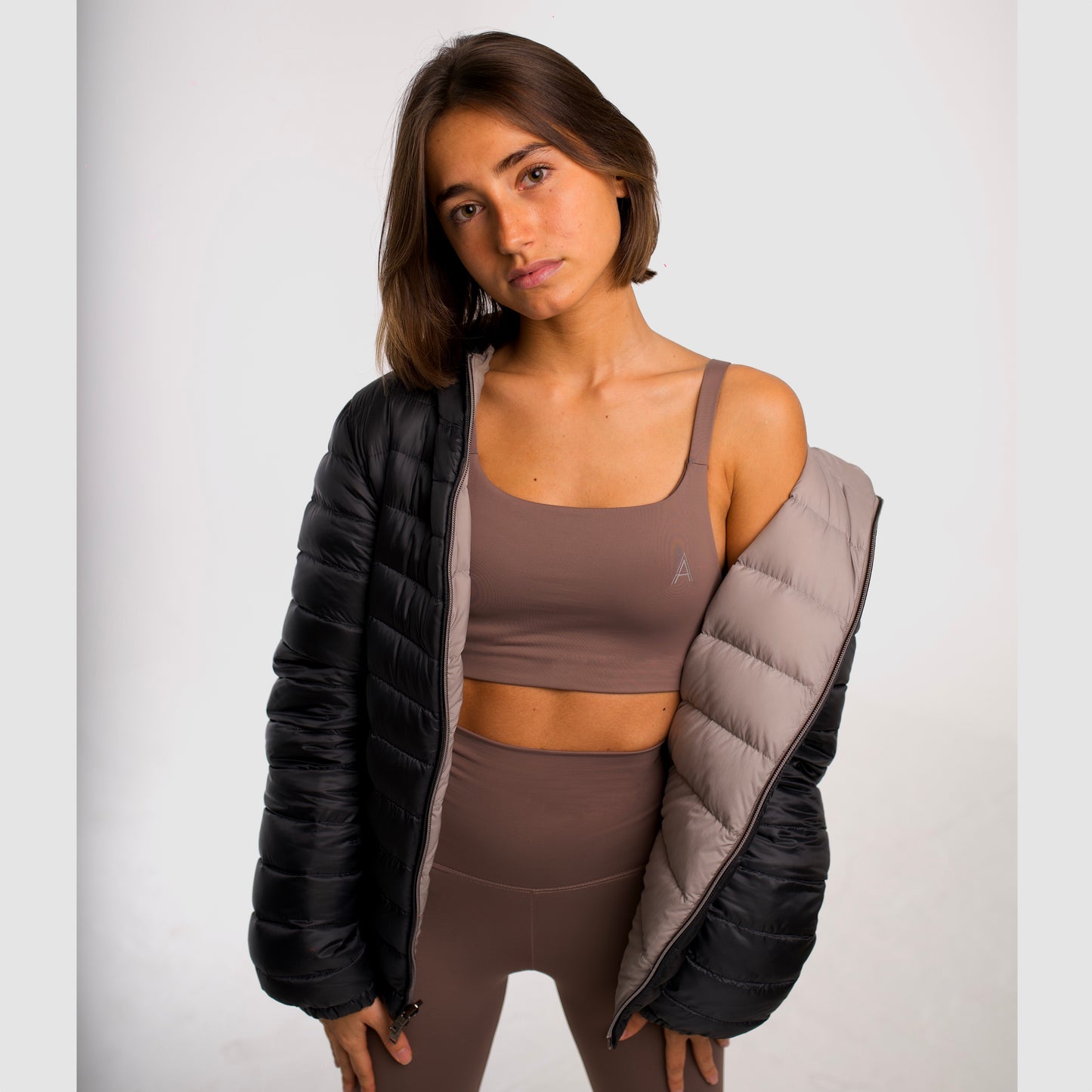 Women's camel sports top. Cross-strap bra. Elastic chest strap for comfort and support. Lightweight, breathable and comfortable bra. Removable cups. Top deportivo de mujer beige. Sujetador de tirantes cruzados. Tira elástica en el pecho ofreciendo comodidad y sujeción. Sujetador cómo, ligero y transpirable. Top con copas extraibles.