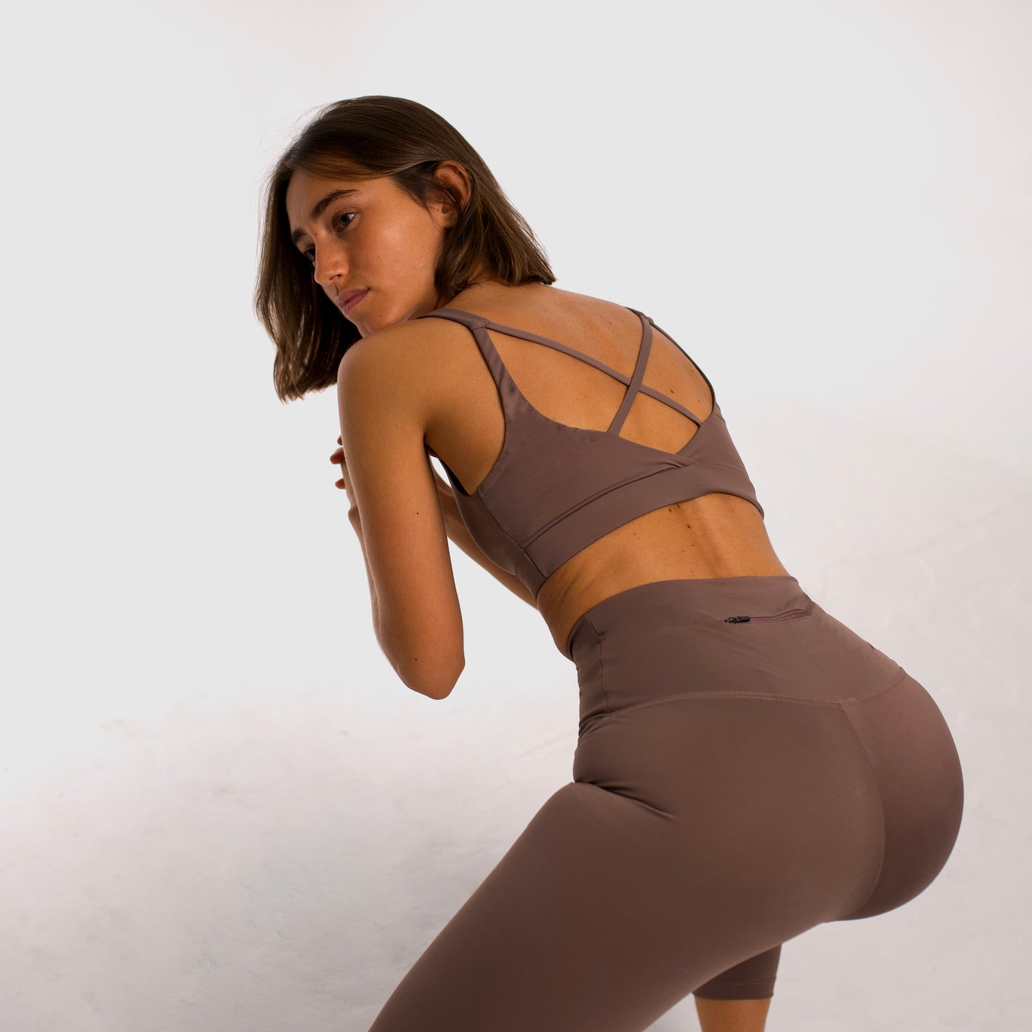 Women's camel sports top. Cross-strap bra. Elastic chest strap for comfort and support. Lightweight, breathable and comfortable bra. Removable cups. Top deportivo de mujer beige. Sujetador de tirantes cruzados. Tira elástica en el pecho ofreciendo comodidad y sujeción. Sujetador cómo, ligero y transpirable. Top con copas extraibles. 