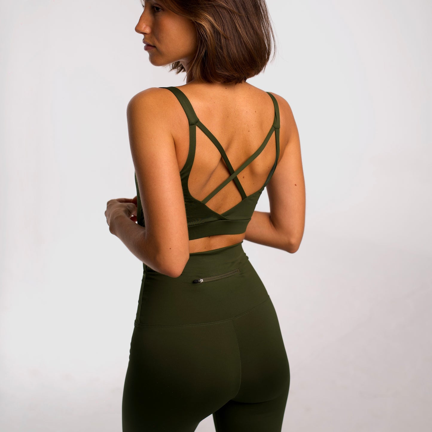 Women's khaki sports top. Cross-strap bra. Elastic chest strap for comfort and support. Lightweight, breathable and comfortable bra. Removable cups. Top deportivo de mujer khaki. Sujetador de tirantes cruzados. Tira elástica en el pecho ofreciendo comodidad y sujeción. Sujetador cómo, ligero y transpirable. Top con copas extraibles.