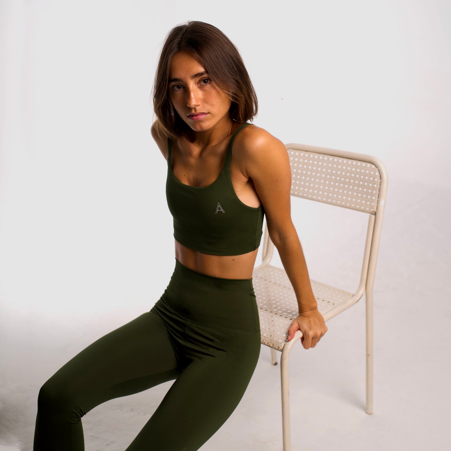 Women's khaki sports top. Cross-strap bra. Elastic chest strap for comfort and support. Lightweight, breathable and comfortable bra. Removable cups. Top deportivo de mujer khaki. Sujetador de tirantes cruzados. Tira elástica en el pecho ofreciendo comodidad y sujeción. Sujetador cómo, ligero y transpirable. Top con copas extraibles.