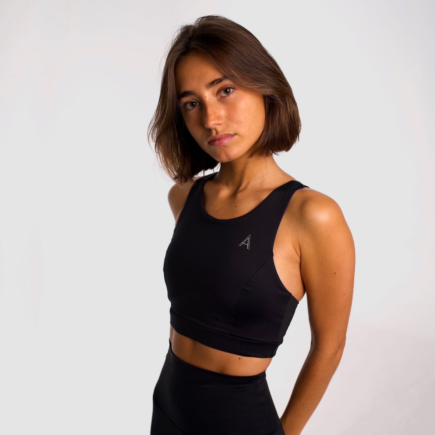 Women's black sports top. Long cut bra. Elastic chest strap for comfort and support. Lightweight, breathable and comfortable bra. Removable cups. Top deportivo de mujer color negro. Sujetador de corte largo. Tira elástica en el pecho ofreciendo comodidad y sujeción. Sujetador cómo, ligero y transpirable. Top con copas extraibles. 