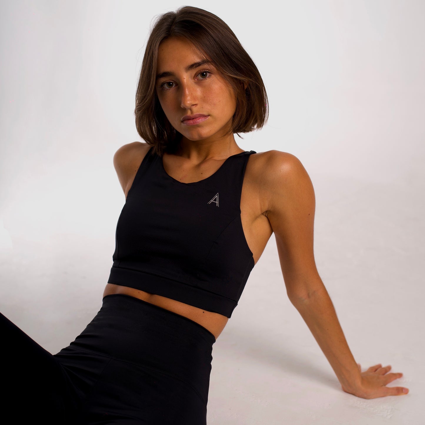 Women's black sports top. Long cut bra. Elastic chest strap for comfort and support. Lightweight, breathable and comfortable bra. Removable cups. Top deportivo de mujer color negro. Sujetador de corte largo. Tira elástica en el pecho ofreciendo comodidad y sujeción. Sujetador cómo, ligero y transpirable. Top con copas extraibles.