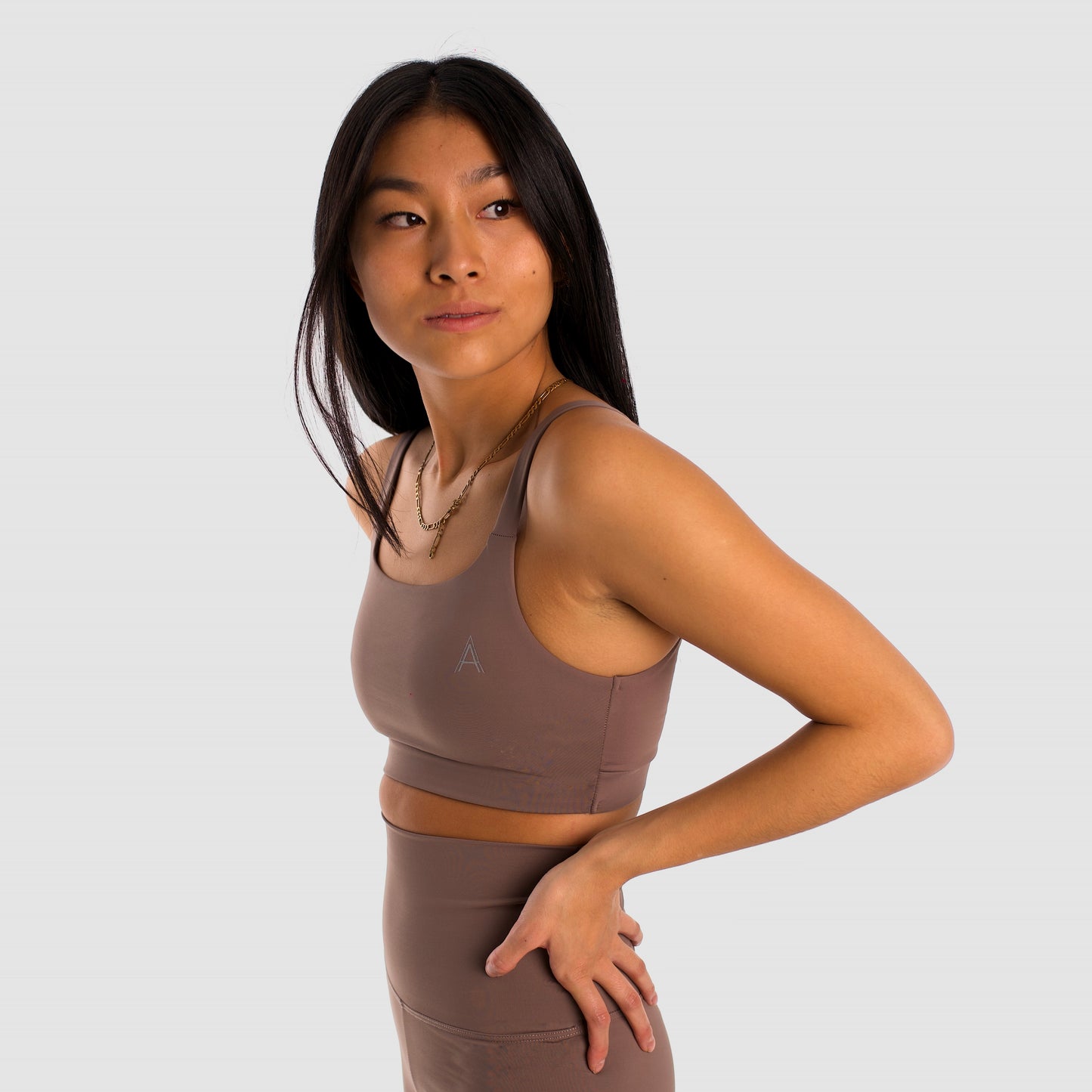 Women's camel sports top. Cross-strap bra. Elastic chest strap for comfort and support. Lightweight, breathable and comfortable bra. Removable cups. Top deportivo de mujer beige. Sujetador de tirantes cruzados. Tira elástica en el pecho ofreciendo comodidad y sujeción. Sujetador cómo, ligero y transpirable. Top con copas extraibles.