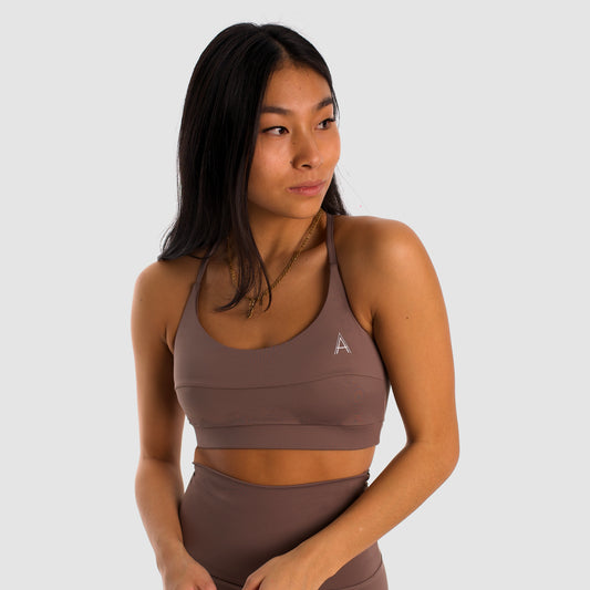 Women's camel sports top. Cross-strap bra. Elastic chest strap for comfort and support. Lightweight, breathable and comfortable bra. Removable cups. Top Deportivo mujer color beige. Sujetador de tirantes cruzados. Tira elástica en el pecho ofreciendo comodidad y sujeción. Sujetador cómo, ligero y transpirable. Top con copas extraibles. 