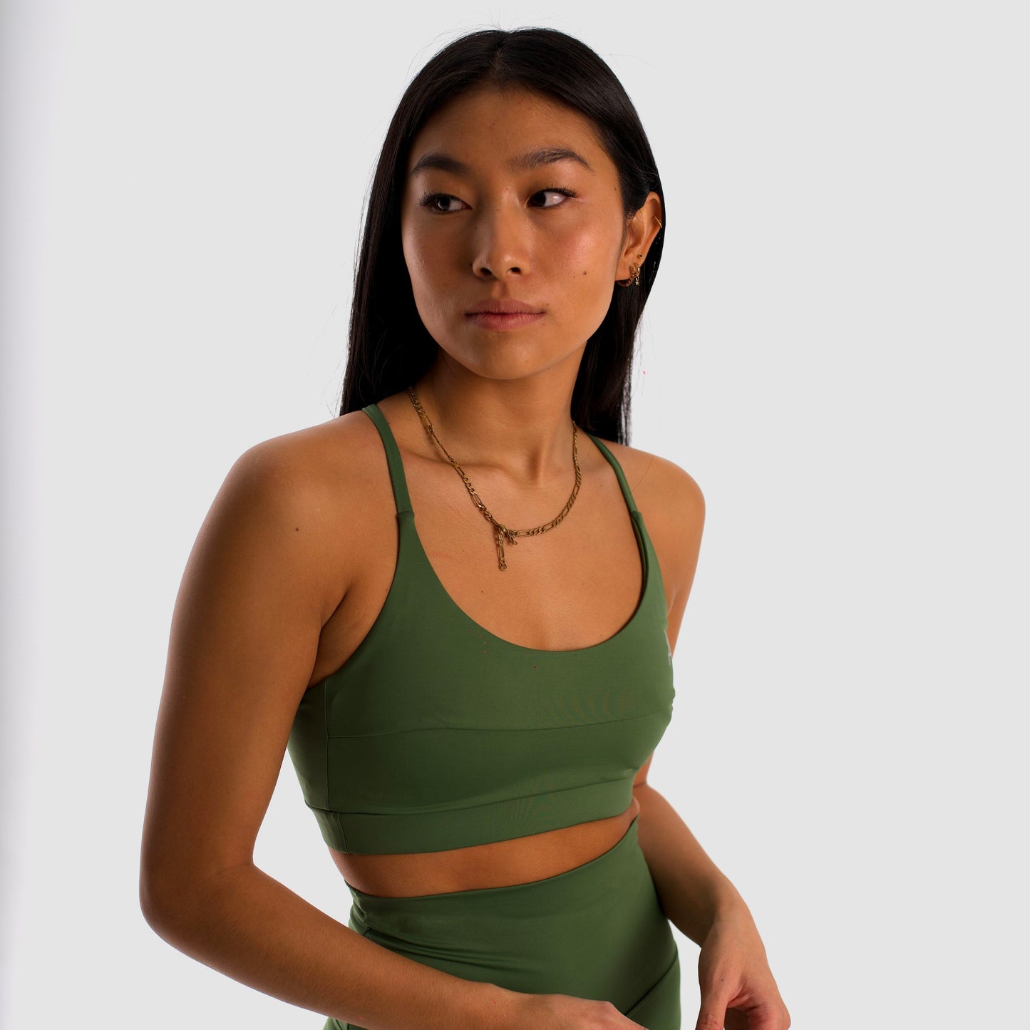 Women's olive green sports bra. Cross-strap bra. Lightweight, breathable and comfortable bra. Removable cups. Top Deportivo mujer verde oliva. Sujetador de tirantes cruzados. Tira elástica en el pecho ofreciendo comodidad y sujeción. Sujetador cómodo, ligero y transpirable. Top con copas extraíbles. 