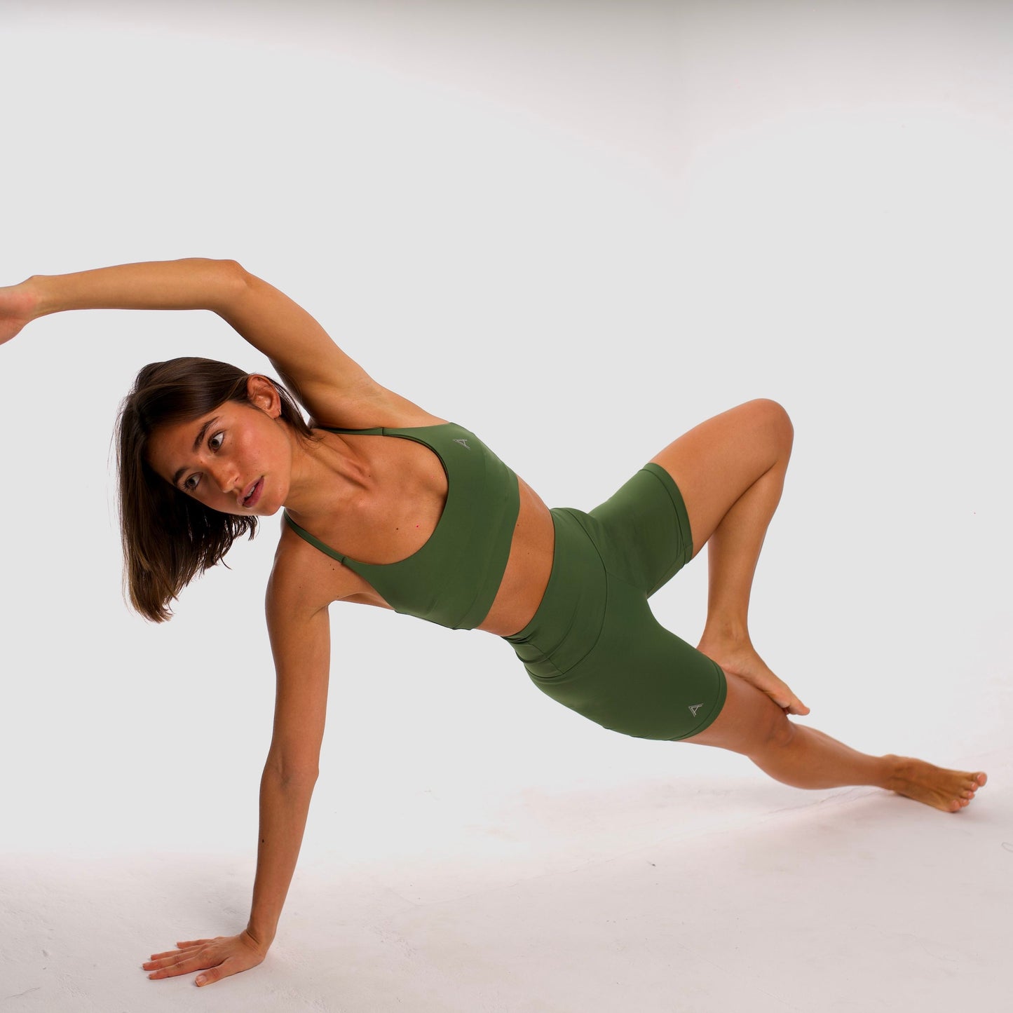 Women's olive green sports bra. Cross-strap bra. Lightweight, breathable and comfortable bra. Removable cups. Top Deportivo mujer verde oliva. Sujetador de tirantes cruzados. Tira elástica en el pecho ofreciendo comodidad y sujeción. Sujetador cómodo, ligero y transpirable. Top con copas extraíbles.