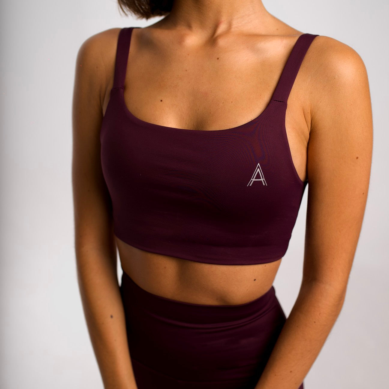 Women's purple sports top. Cross-strap bra. Elastic chest strap for comfort and support. Lightweight, breathable and comfortable bra. Removable cups. Top deportivo de mujer morado. Sujetador de tirantes cruzados. Tira elástica en el pecho ofreciendo comodidad y sujeción. Sujetador cómo, ligero y transpirable. Top con copas extraibles. 