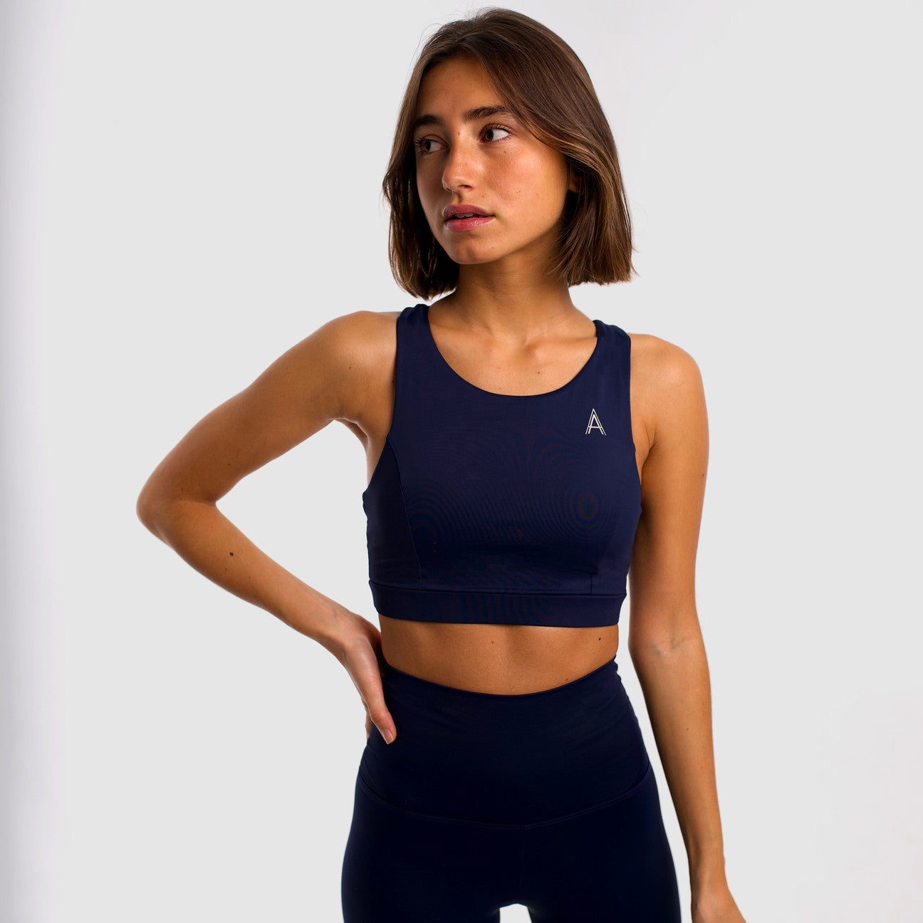 Women's navy blue sports top. Long cut bra. Elastic chest strap for comfort and support. Lightweight, breathable and comfortable bra. Removable cups. Top deportivo de mujer color azul marino. Sujetador de corte largo. Tira elástica en el pecho ofreciendo comodidad y sujeción. Sujetador cómo, ligero y transpirable. Top con copas extraibles.