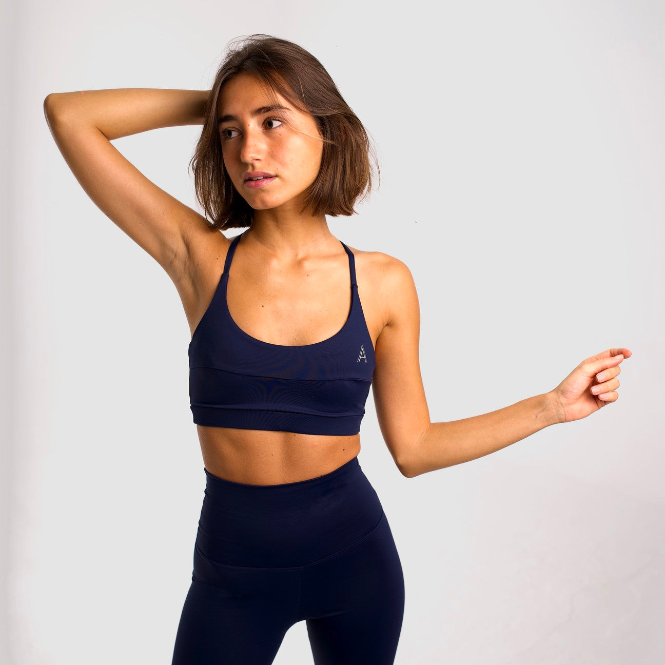 Women's navy blue sports top. Cross-strap bra. Elastic chest strap for comfort and support. Lightweight, breathable and comfortable bra. Removable cups. Top Deportivo mujer color azul marino. Sujetador de tirantes cruzados. Tira elástica en el pecho ofreciendo comodidad y sujeción. Sujetador cómo, ligero y transpirable. Top con copas extraibles. 