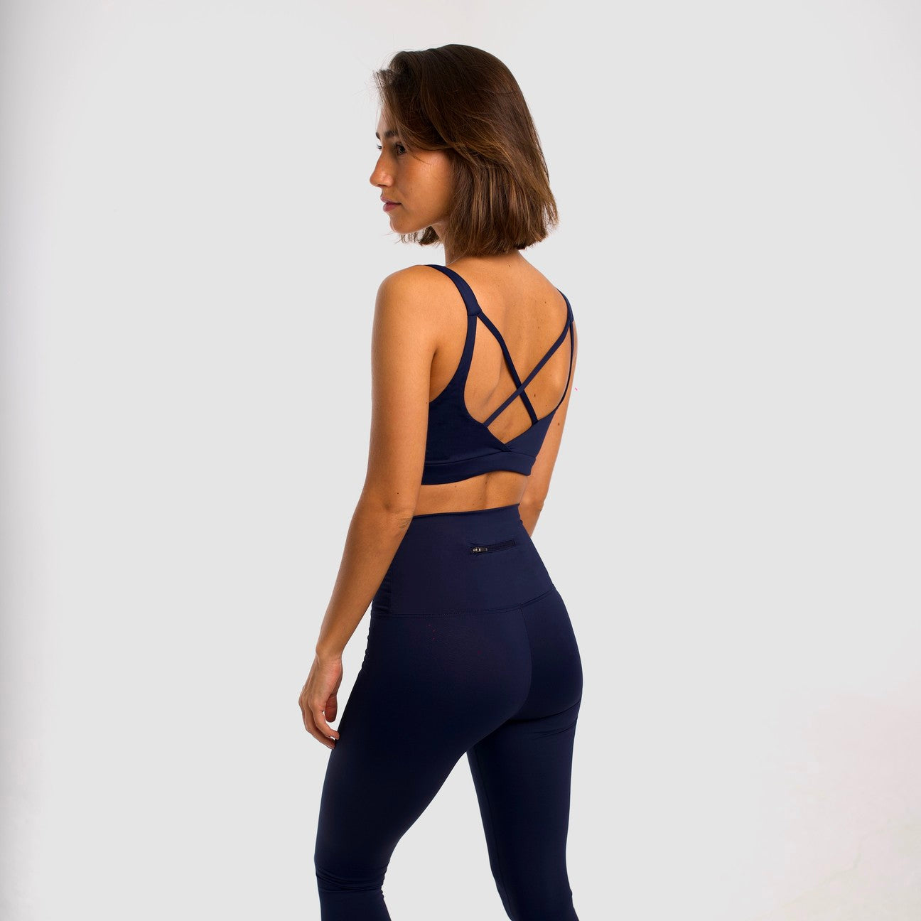 Women's navy blue sports top. Cross-strap bra. Elastic chest strap for comfort and support. Lightweight, breathable and comfortable bra. Removable cups. Top deportivo de mujer azul marino. Sujetador de tirantes cruzados. Tira elástica en el pecho ofreciendo comodidad y sujeción. Sujetador cómo, ligero y transpirable. Top con copas extraibles.