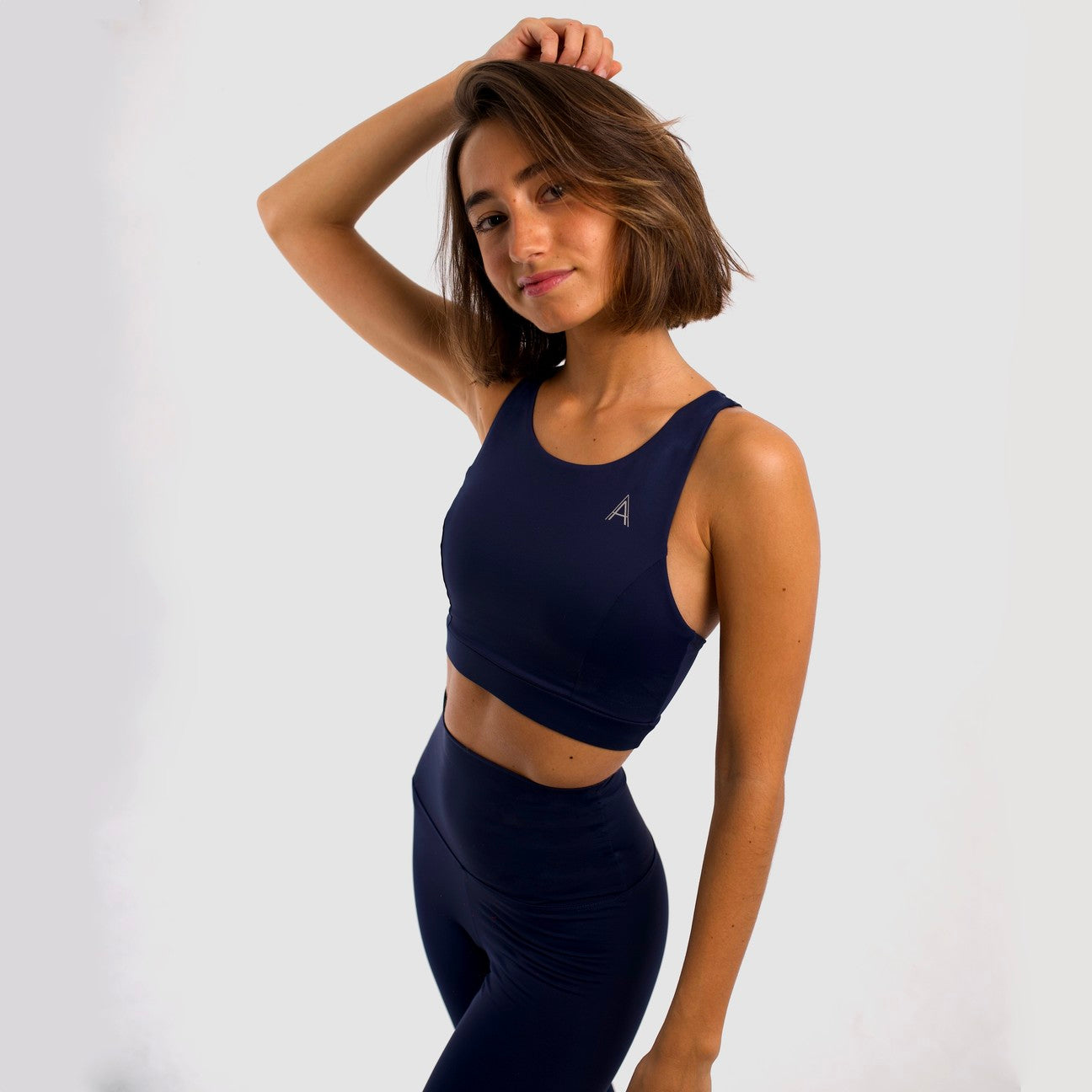 Women's navy blue sports top. Long cut bra. Elastic chest strap for comfort and support. Lightweight, breathable and comfortable bra. Removable cups. Top deportivo de mujer color azul marino. Sujetador de corte largo. Tira elástica en el pecho ofreciendo comodidad y sujeción. Sujetador cómo, ligero y transpirable. Top con copas extraibles.