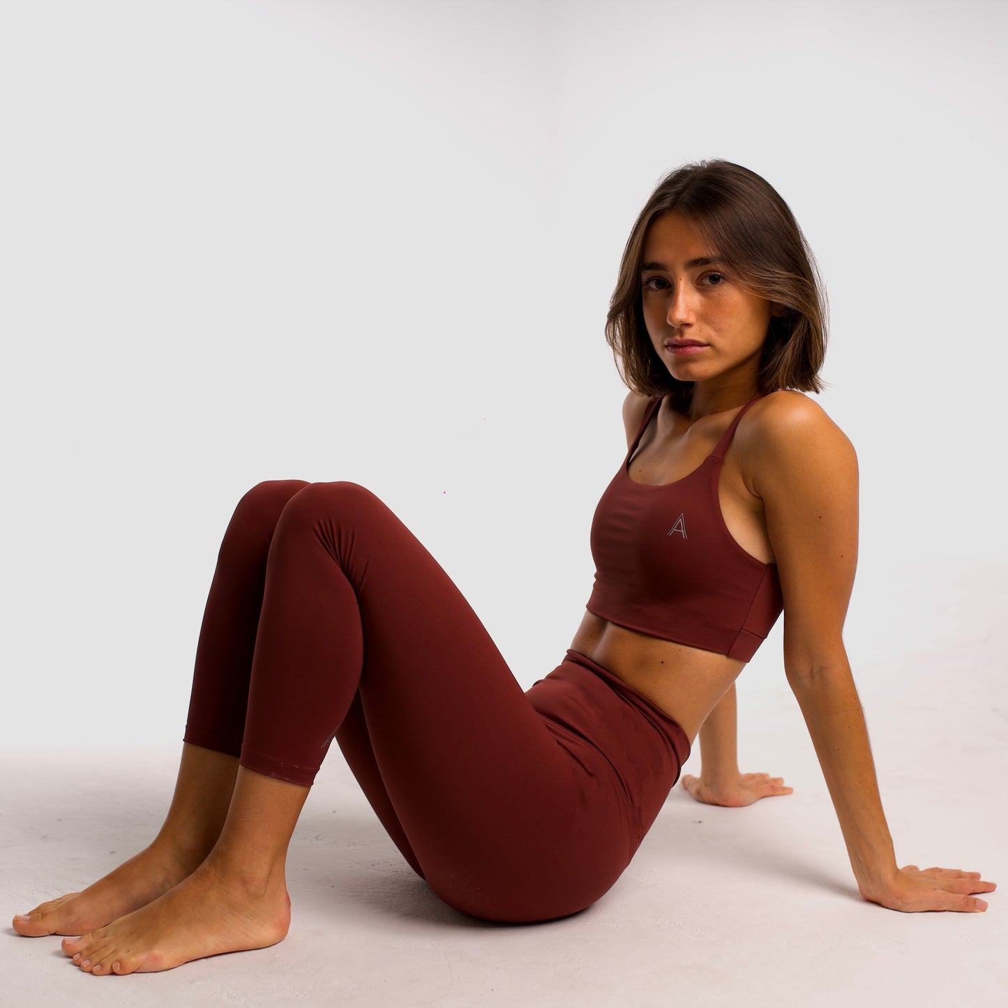 Women's maroon sports top. Cross-strap bra. Elastic chest strap for comfort and support. Lightweight, breathable and comfortable bra. Removable cups. Top deportivo de mujer granate. Sujetador de tirantes cruzados. Tira elástica en el pecho ofreciendo comodidad y sujeción. Sujetador cómo, ligero y transpirable. Top con copas extraibles. 