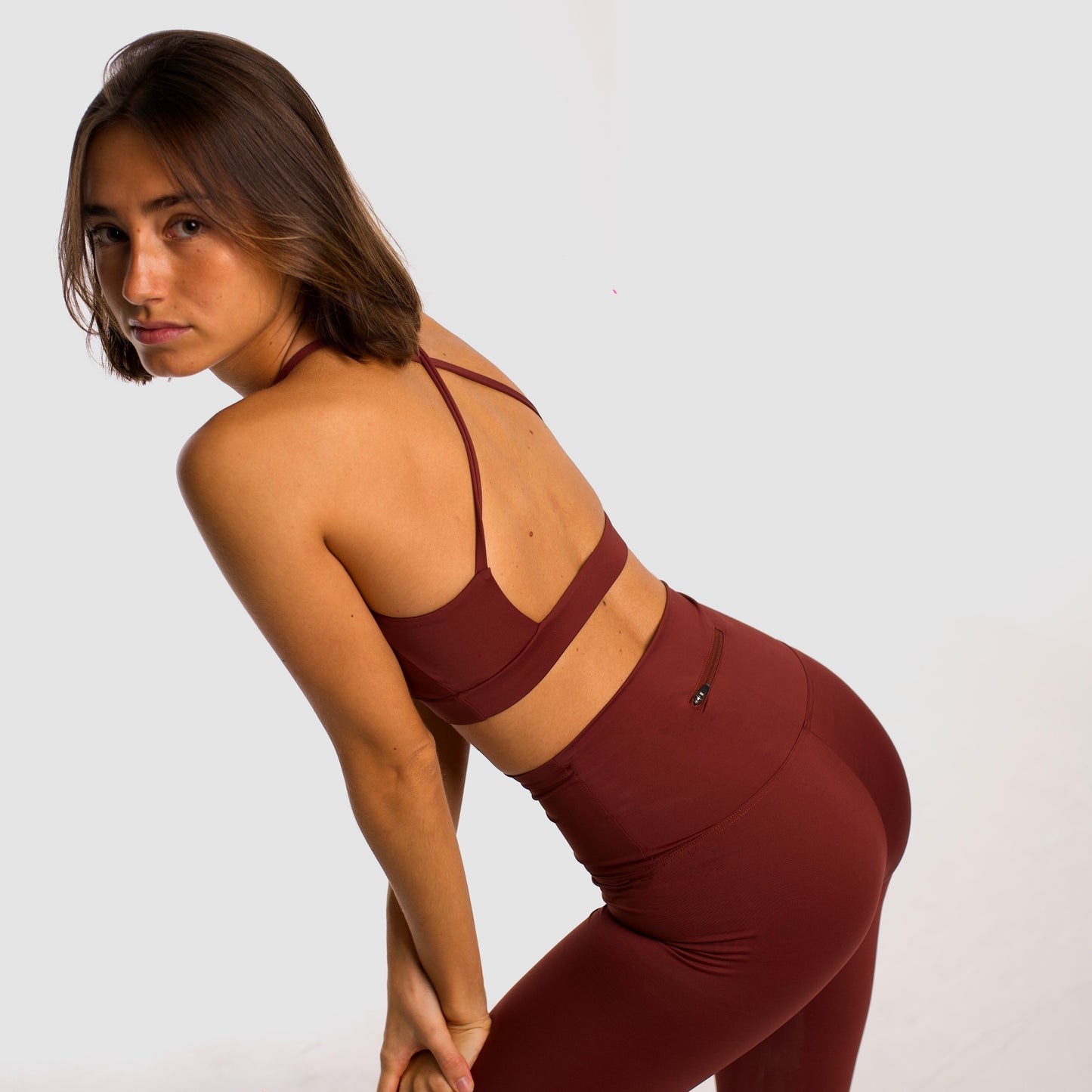 Women's maroon sports top. Cross-strap bra. Elastic chest strap for comfort and support. Lightweight, breathable and comfortable bra. Removable cups. Top Deportivo mujer color granate. Sujetador de tirantes cruzados. Tira elástica en el pecho ofreciendo comodidad y sujeción. Sujetador cómo, ligero y transpirable. Top con copas extraibles.