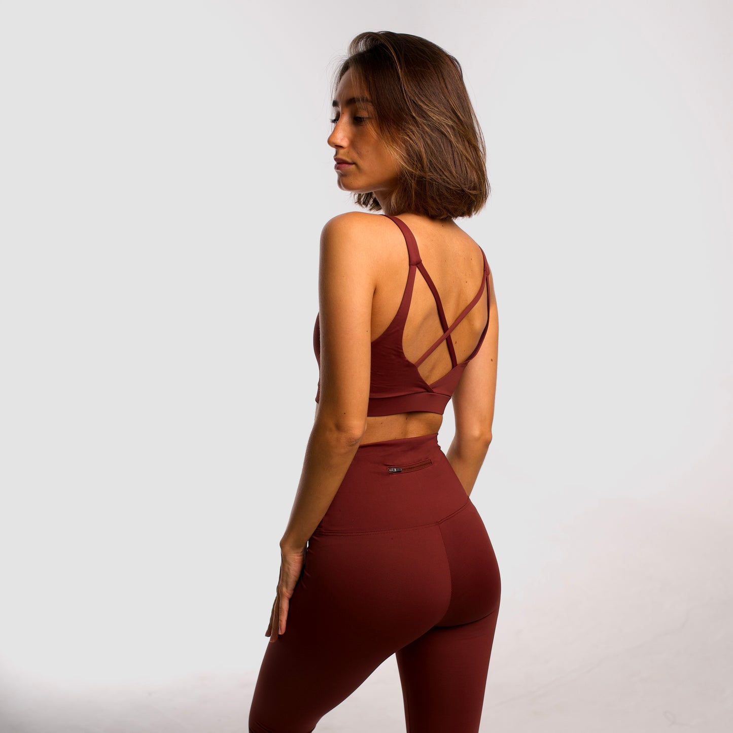 Women's maroon sports top. Cross-strap bra. Elastic chest strap for comfort and support. Lightweight, breathable and comfortable bra. Removable cups. Top deportivo de mujer granate. Sujetador de tirantes cruzados. Tira elástica en el pecho ofreciendo comodidad y sujeción. Sujetador cómo, ligero y transpirable. Top con copas extraibles. 