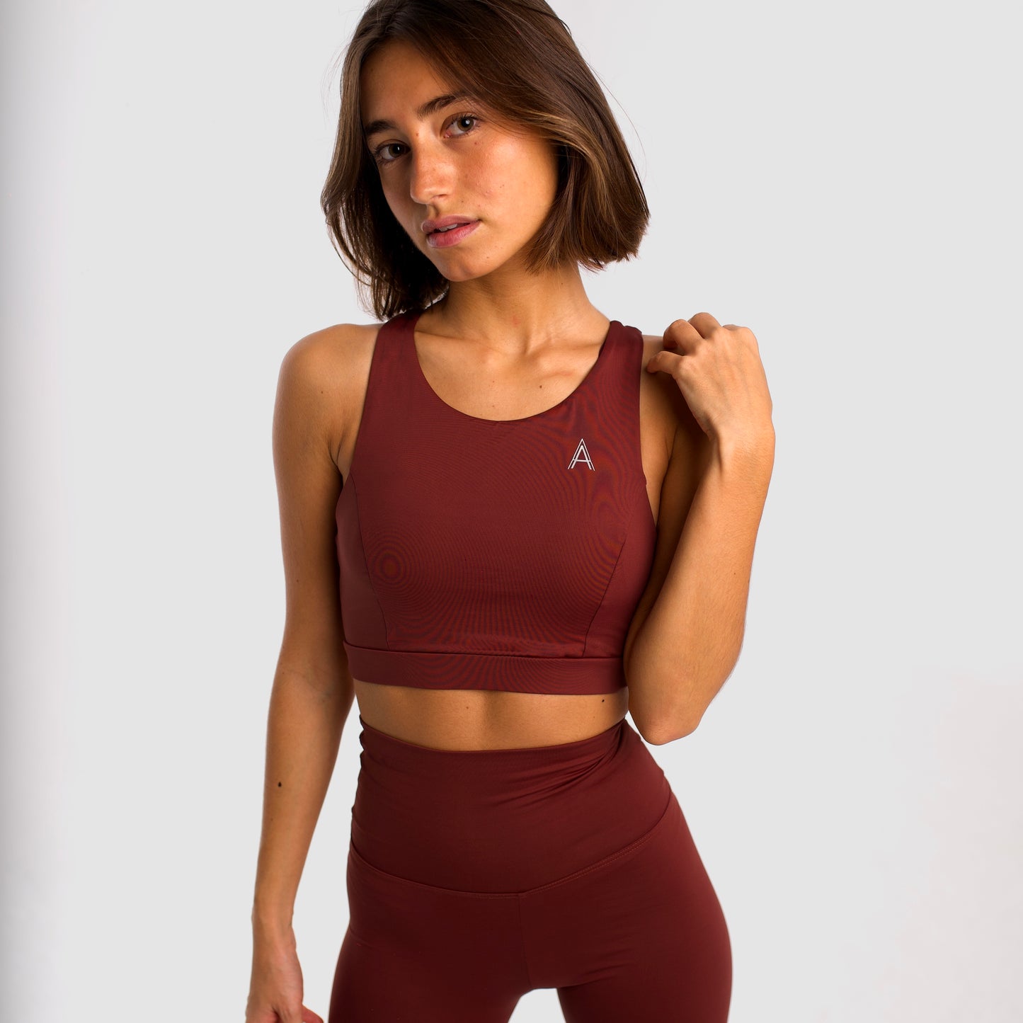 Women's maroon sports top. Long cut bra. Elastic chest strap for comfort and support. Lightweight, breathable and comfortable bra. Removable cups. Top deportivo de mujer color granate. Sujetador de corte largo. Tira elástica en el pecho ofreciendo comodidad y sujeción. Sujetador cómo, ligero y transpirable. Top con copas extraibles. 