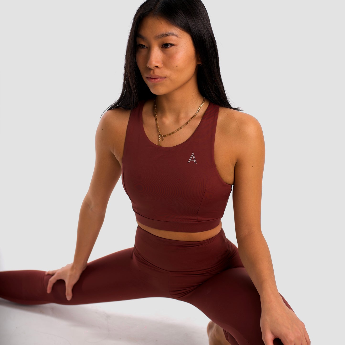 Women's maroon sports top. Long cut bra. Elastic chest strap for comfort and support. Lightweight, breathable and comfortable bra. Removable cups. Top deportivo de mujer color granate. Sujetador de corte largo. Tira elástica en el pecho ofreciendo comodidad y sujeción. Sujetador cómo, ligero y transpirable. Top con copas extraibles. 