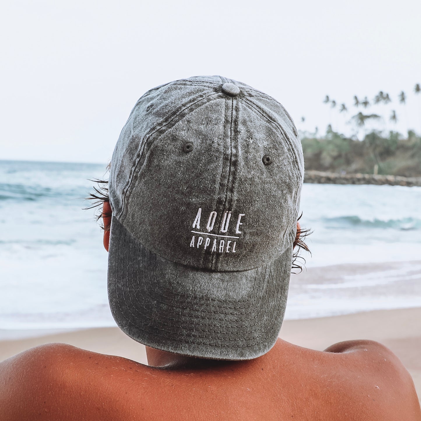 Gorra Aqüe Apparel negra efecto lavado, ajustable. Black Aqüe Apparel cap washed effect fabric, adjustable strap-back closure. 6 Panel Dad Cap. 100% cotton. 