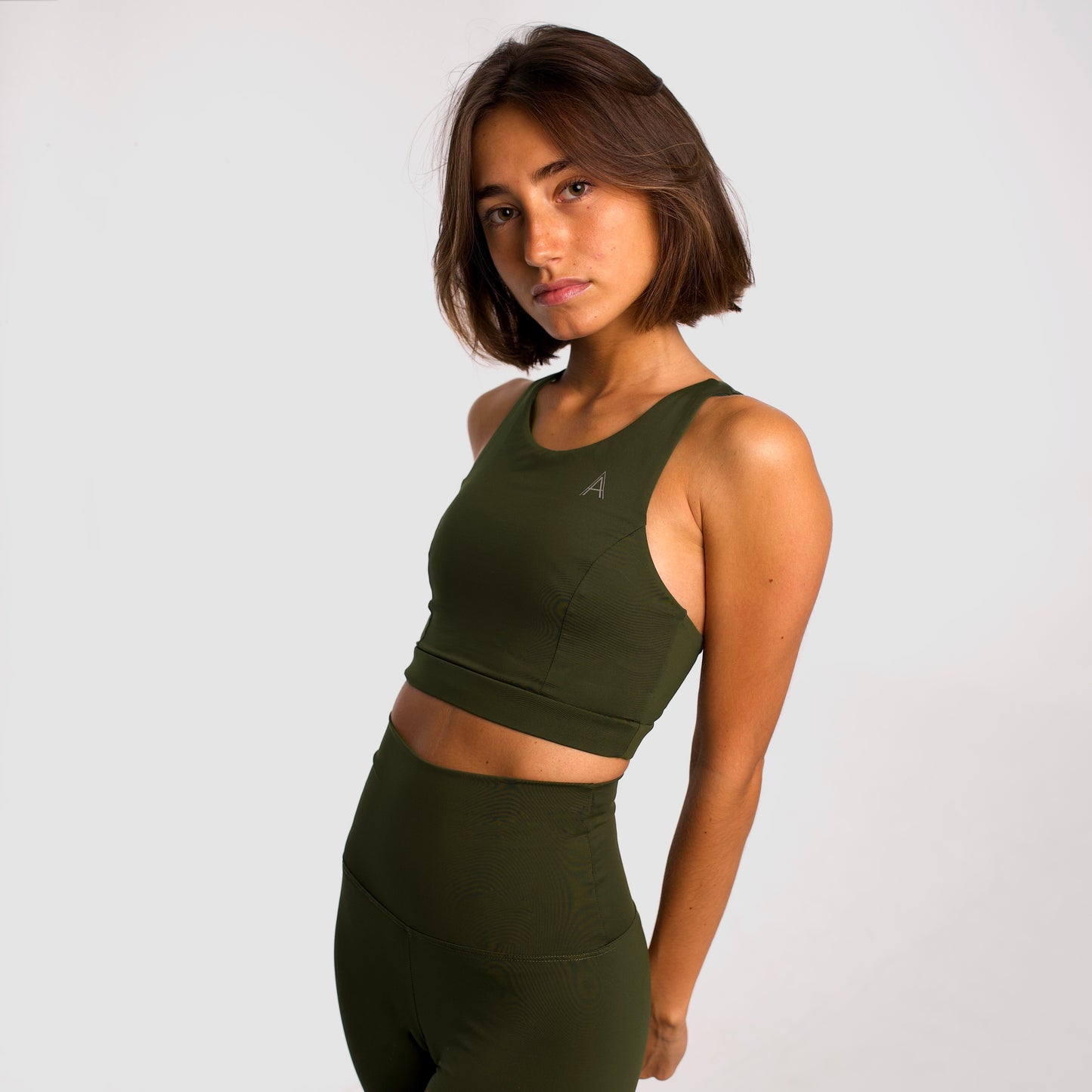 Women's khaki sports top. Long cut bra. Elastic chest strap for comfort and support. Lightweight, breathable and comfortable bra. Removable cups. Top deportivo de mujer color khaki. Sujetador de corte largo. Tira elástica en el pecho ofreciendo comodidad y sujeción. Sujetador cómo, ligero y transpirable. Top con copas extraibles. 