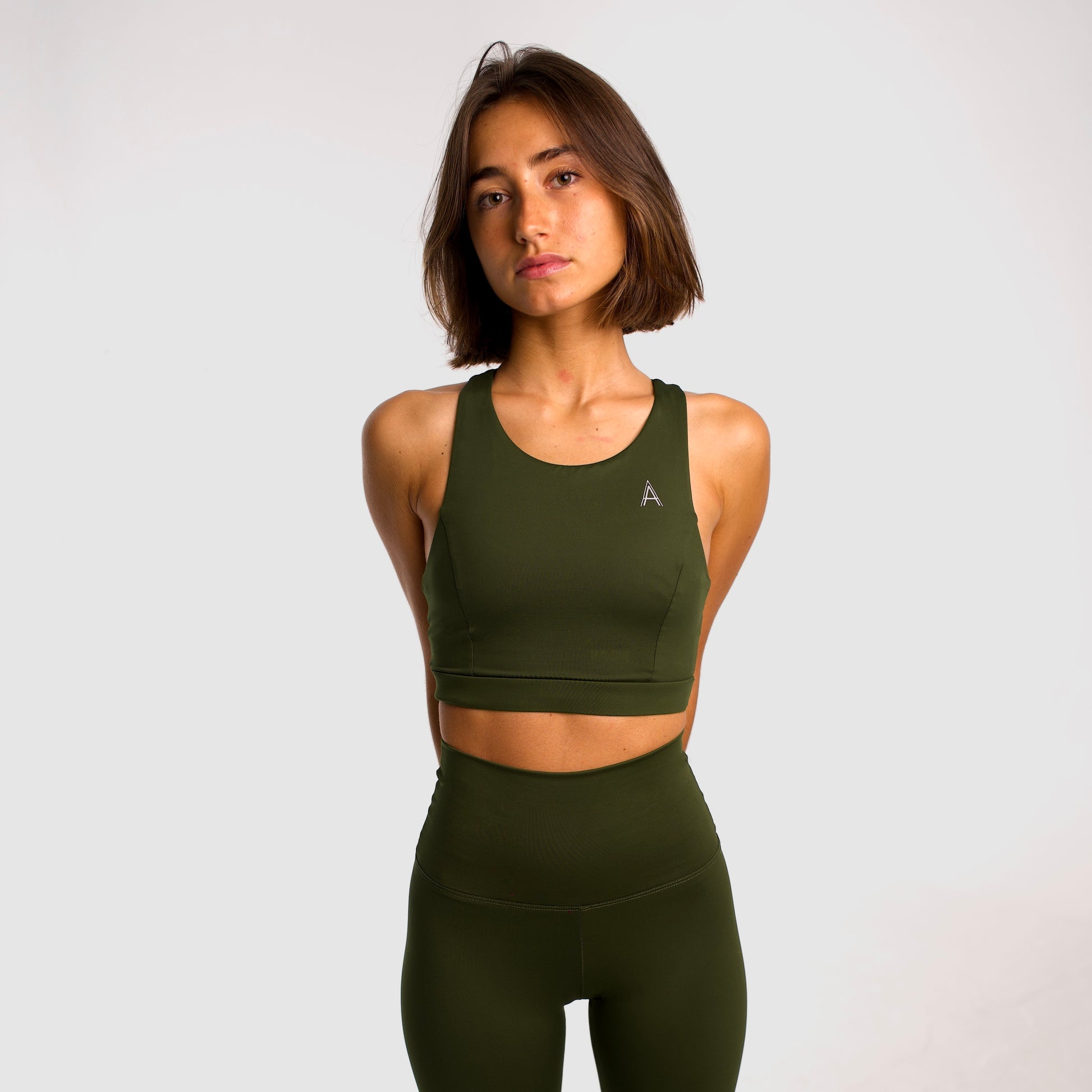 Women's khaki sports top. Long cut bra. Elastic chest strap for comfort and support. Lightweight, breathable and comfortable bra. Removable cups. Top deportivo de mujer color khaki. Sujetador de corte largo. Tira elástica en el pecho ofreciendo comodidad y sujeción. Sujetador cómo, ligero y transpirable. Top con copas extraibles. 