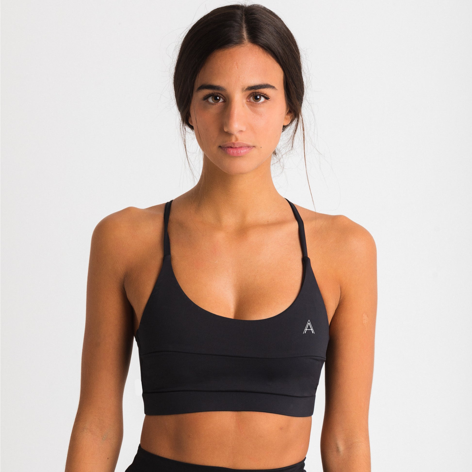 Women's black sports top. Cross-strap bra. Elastic chest strap for comfort and support. Lightweight, breathable and comfortable bra. Removable cups. Top Deportivo mujer negro. Sujetador de tirantes cruzados. Tira elástica en el pecho ofreciendo comodidad y sujeción. Sujetador cómo, ligero y transpirable. Top con copas extraibles. 