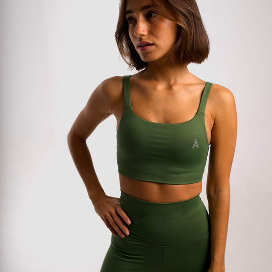 Women's olive green sports bra. Cross-strap bra. Lightweight, breathable and comfortable bra. Removable cups. Top deportivo de mujer verde oliva. Sujetador de tirantes cruzados. Tira elástica en el pecho ofreciendo comodidad y sujeción. Sujetador cómodo, ligero y transpirable. Top con copas extraíbles. 