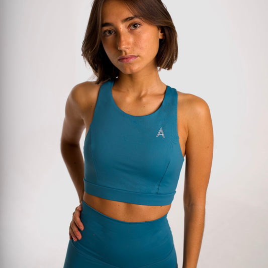 Women's canard blue sports bra. Long cut bra. Lightweight, breathable and comfortable bra. Removable cups. Top deportivo de mujer color azul pato. Sujetador de corte largo. Tira elástica en el pecho ofreciendo comodidad y sujeción. Sujetador cómodo, ligero y transpirable. Top con copas extraíbles. 