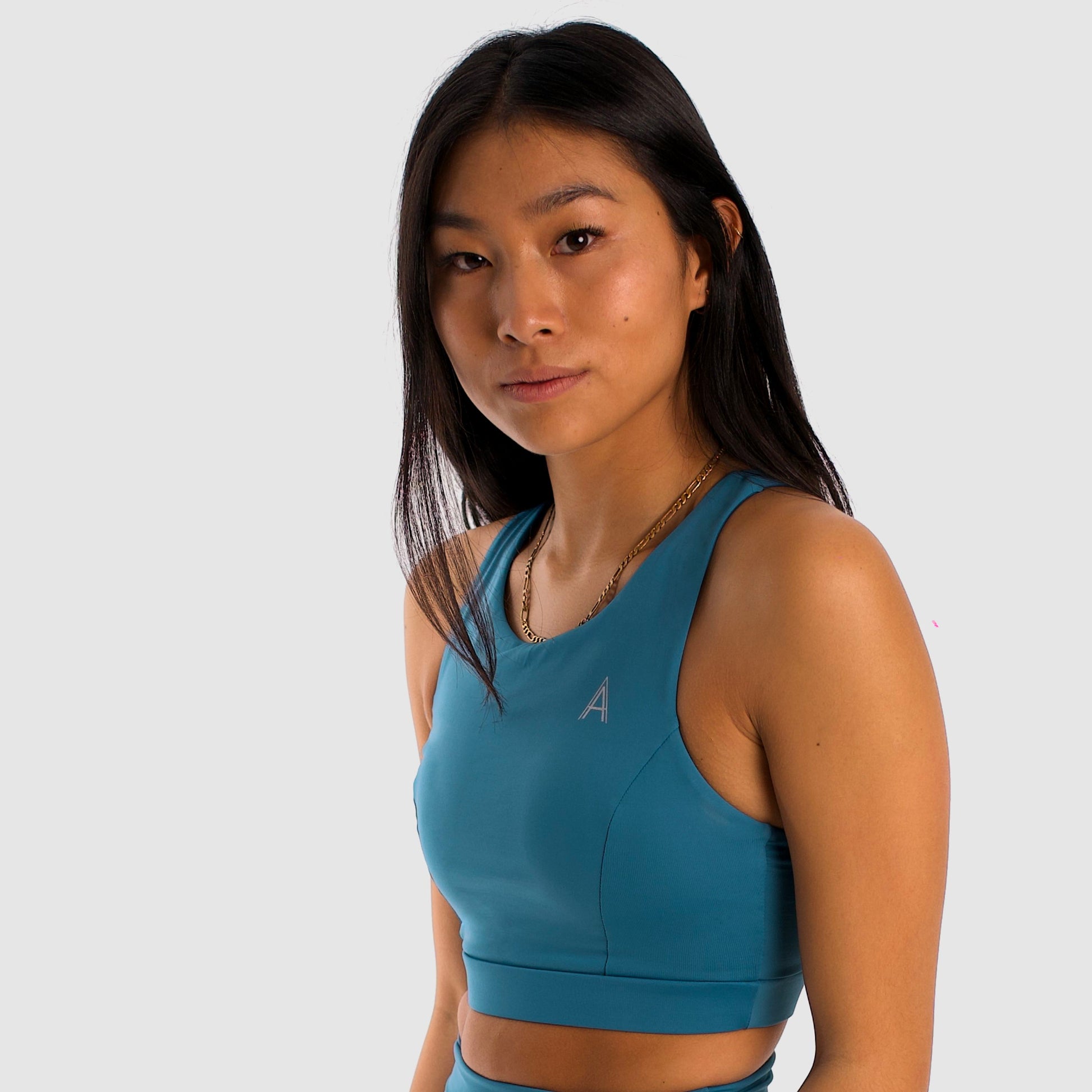 Women's canard blue sports bra. Long cut bra. Lightweight, breathable and comfortable bra. Removable cups. Top deportivo de mujer color azul pato. Sujetador de corte largo. Tira elástica en el pecho ofreciendo comodidad y sujeción. Sujetador cómodo, ligero y transpirable. Top con copas extraíbles. 