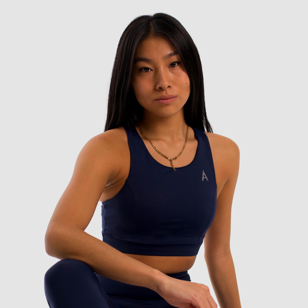 Women's navy blue sports top. Long cut bra. Elastic chest strap for comfort and support. Lightweight, breathable and comfortable bra. Removable cups. Top deportivo de mujer color azul marino. Sujetador de corte largo. Tira elástica en el pecho ofreciendo comodidad y sujeción. Sujetador cómo, ligero y transpirable. Top con copas extraibles. 