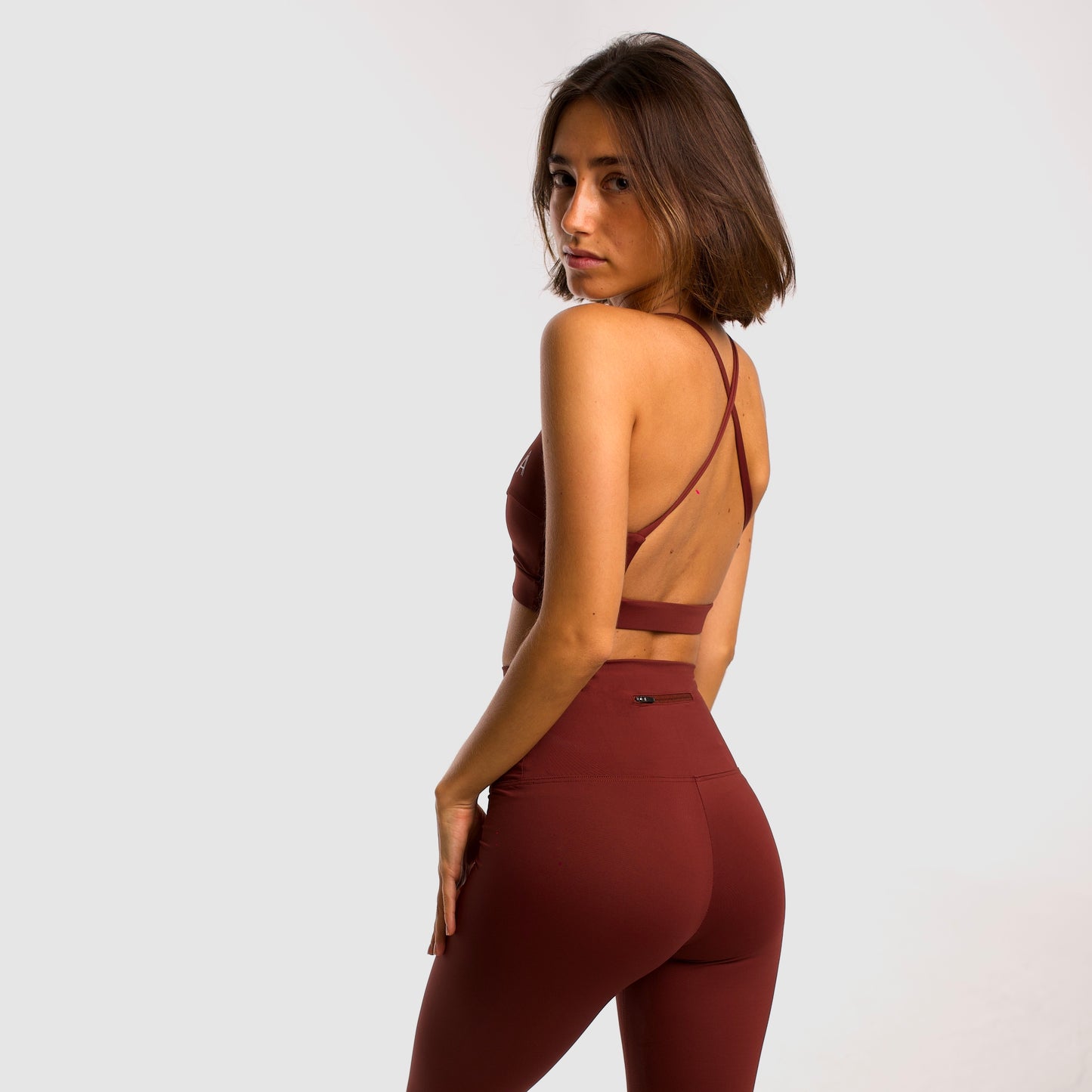 Women's maroon sports top. Cross-strap bra. Elastic chest strap for comfort and support. Lightweight, breathable and comfortable bra. Removable cups. Top Deportivo mujer color granate. Sujetador de tirantes cruzados. Tira elástica en el pecho ofreciendo comodidad y sujeción. Sujetador cómo, ligero y transpirable. Top con copas extraibles.