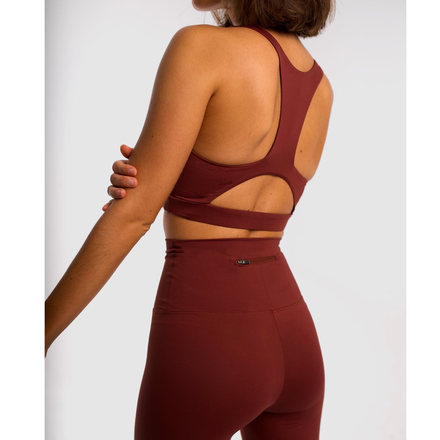 Women's maroon sports top. Long cut bra. Elastic chest strap for comfort and support. Lightweight, breathable and comfortable bra. Removable cups. Top deportivo de mujer color granate. Sujetador de corte largo. Tira elástica en el pecho ofreciendo comodidad y sujeción. Sujetador cómo, ligero y transpirable. Top con copas extraibles. 